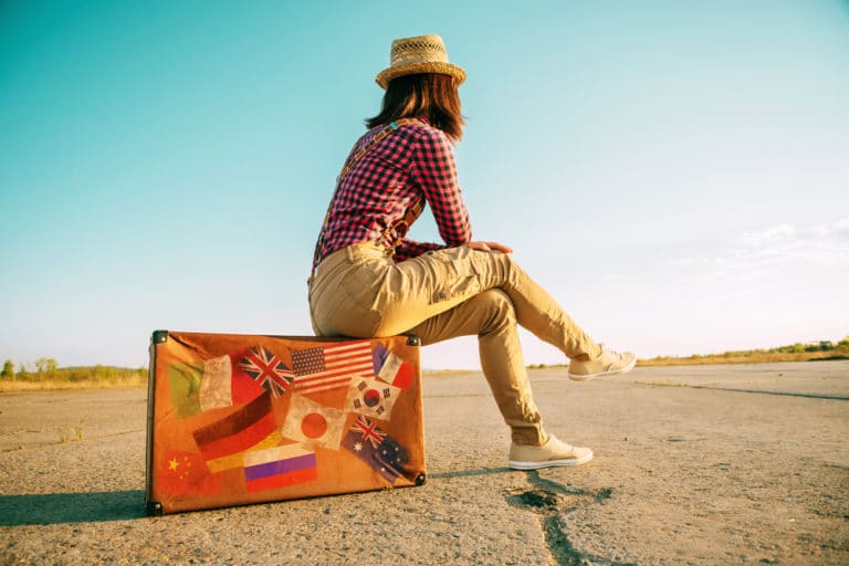 Woman sitting on a suitcase contemplating the open road